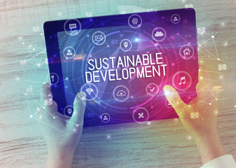 Close-up of a tablet with SUSTAINABLE DEVELOPMENT inscription, innovative technology concept