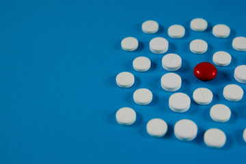 many white pills and one red on a blue background