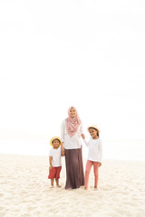Asian kids having leisure time with their mother at the beach.