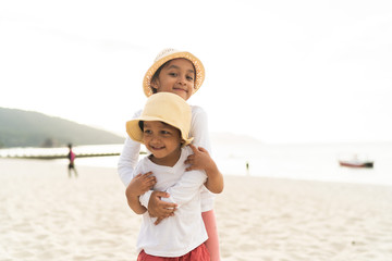 Asian kids smiling while playing at the beach.