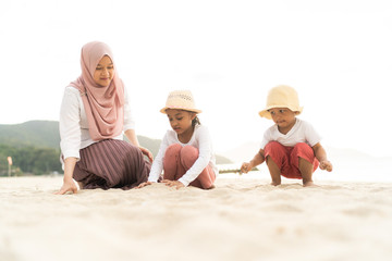 Asian kids having leisure time with their mother at the beach.