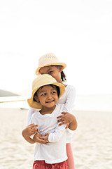 Asian kids smiling while playing at the beach.