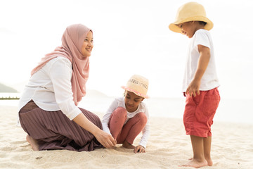 Asian kids having leisure time with their mother at the beach.