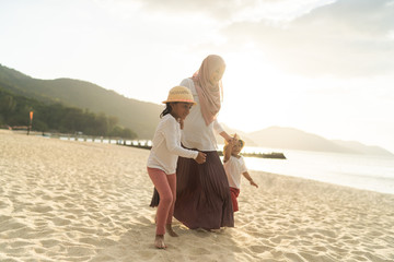Asian kids having leisure time with their mother at the beach.