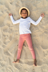 Kids lying down happily together on a beach sand