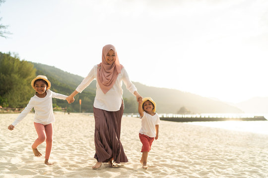 Asian kids having leisure time with their mother at the beach.