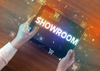 Close-up of a hand holding tablet with SHOWROOM inscription, online shopping concept