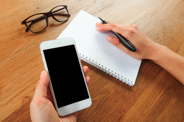 female hands holding smart phone on wooden background  , place for your text