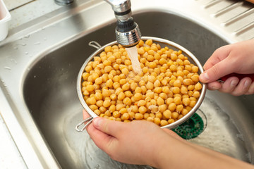 Woman hands washing fresh chickpeas under the running water, healthy food concept