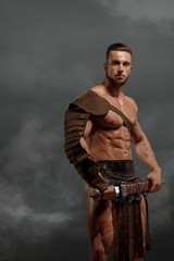 Fototapeta na wymiar Rome gladiator attacking on dramatic outdoor nature. Ancient warrior with sword on blood sand