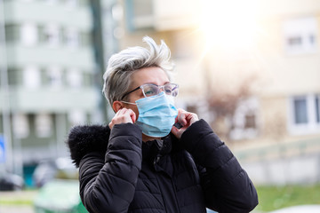 Fototapeta premium COVID-19 Pandemic Coronavirus Woman in city street wearing face mask protective for spreading of disease virus SARS-CoV-2. Girl with surgical mask on face against Coronavirus Disease 2019.