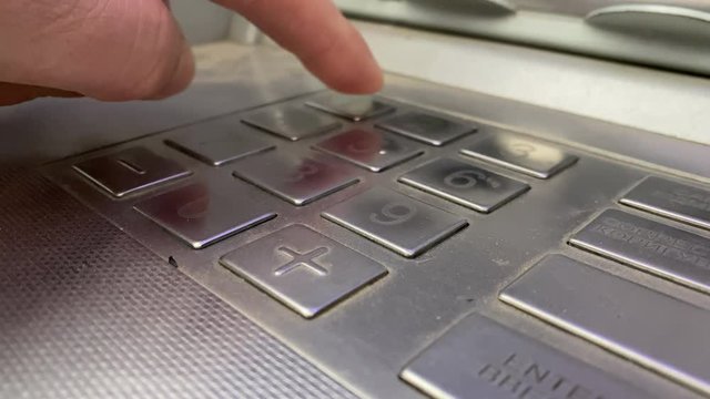 Using street ATM teller machine to manage money, male hand entering pin code on ATM dial panel to withdraw money or make deposit close-up.