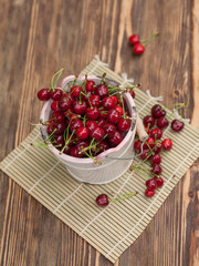Fresh cherries in bowl on wooden table