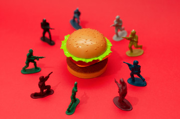 Hamburger surrounded by toy soldiers, burger wars concept or war on fast food concept.