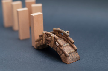 A group of wood blocks crossing a toy bridge. Travel or leadership concept.