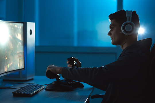 The guy gamer with headphones playing video games in the dark room