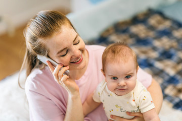 A young mother is talking on the phone in her arms with her baby. The child lacks attention. How to combine motherhood, self-development and personal affairs?