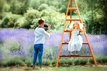 6 years old photographer boy take picture of small beautiful curly blonde girl in lavender field....