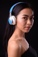 Fototapeta premium Face of young beautiful Asian woman listening to music