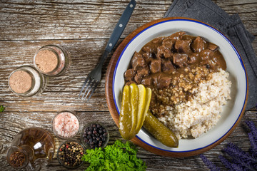 Beef stew served with barley and pickled cucumber.
