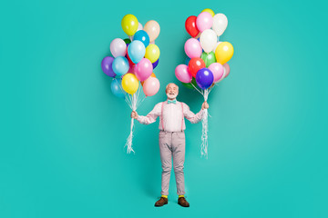 Full size photo of positive cheerful old man hipster hold many air balls enjoy festive occasion event wear good look trousers brown shoes isolated over teal color background