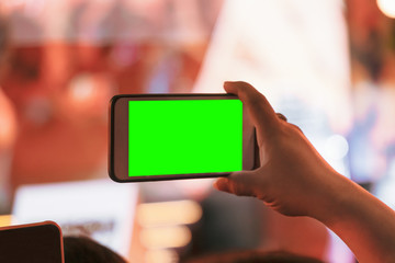Hands of audience crowd people taking photo with mobile smart phone with green screen in party concert.