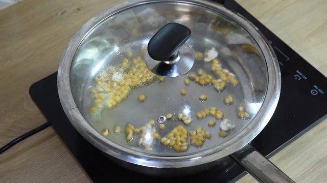 Popcorn starting to explode in a frying pan, HD footage. Squib, burst.