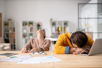 One of managers lying on laptop keypad and his colleague throwing her head back