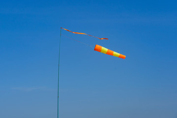 flagpole with wind indicator on a background of blue sky