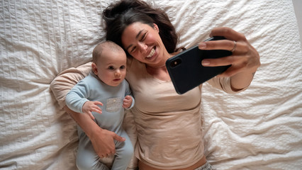 Authentic close up of neo mother and her newborn baby making a selfie or video call to father or...