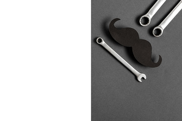 Fathers Day mockup with retro stylish black funny paper moustache and combination wrenches on grey background with copy space. Flat lay, top view, minimal composition