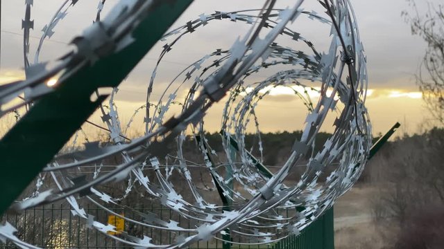 Razor barbed wire mounted on welded wire mesh fence rigid security barrier.