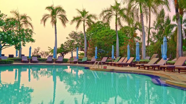 beach chair or pool bed with umbrella around swimming pool at sunset time
