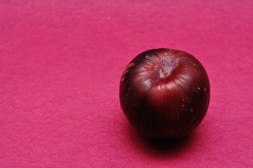 A ripe plum on a pink background