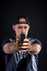 man pointing gun at object, portrait on black background