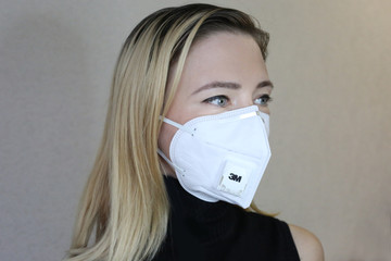 Woman wearing a face mask,  with filter pm 2.5 isolated on gray background. Flu epidemic, dust allergy, protection against virus. Covid 19 virus concept.