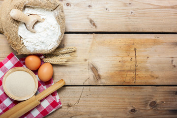 flour, spoon, eggs  and roller on wooden background