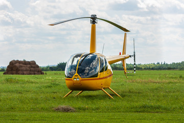 A yellow helicopter parked at an airfield - obrazy, fototapety, plakaty