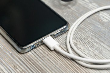 USB cable with smartphone on wood table