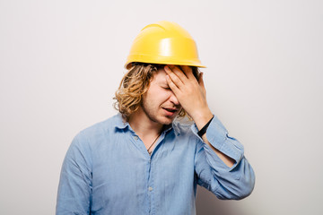 Tired young manual worker - builder, isolated on gray background, close-up studio shot