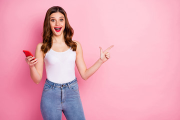 Crazy excited girl addicted social media promoter use smartphone point finger copyspace present incredible ads promotion wear white singlet tank-top jeans denim isolated pink color background