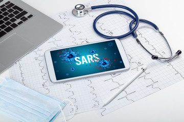 Tablet pc and doctor tools on white surface with SARS inscription, pandemic concept