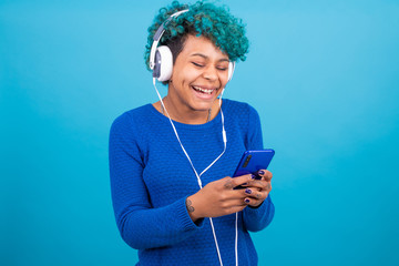 young girl with mobile phone and headphones isolated on color background