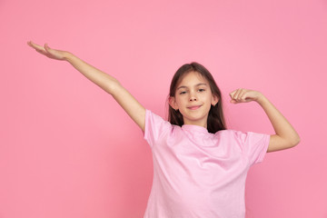 Winner gesture. Caucasian little girl portrait isolated on pink studio background. Cute brunette model in shirt. Concept of human emotions, facial expression, sales, ad, childhood. Copyspace.