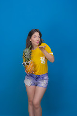 Happy girl holding a pineapple on a blue background