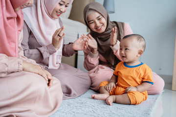 asian muslim mother with her friends enjoy playing with her son when sitting on the floor in the bedroom