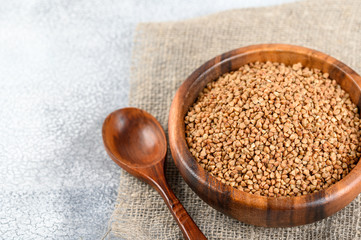 Buckwheats in a wood bowl on a sack cloth and light background.