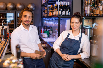 Two young restful workers of cafe standing next to each other in front of camera