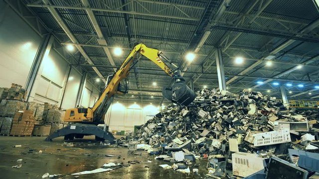 Indoors dumpsite with electronics debris and an excavator