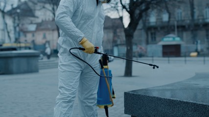 Fototapeta premium Disinfection specialist in white protective clothing handles antibacterial process in empty city during carnitine